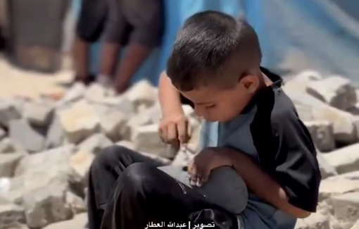 Thumbnail preview image for the video titled: Palestinian child repairs a torn shoe atop rubble under the blazing sun in a Gaza displacement camp