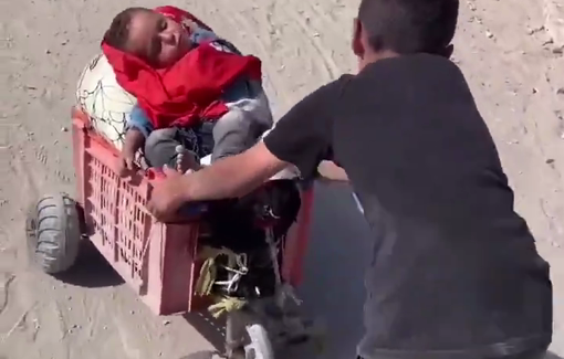 Thumbnail preview image for the video titled: Barefoot child pushes his baby brother's makeshift stroller during displacement from northern Gaza